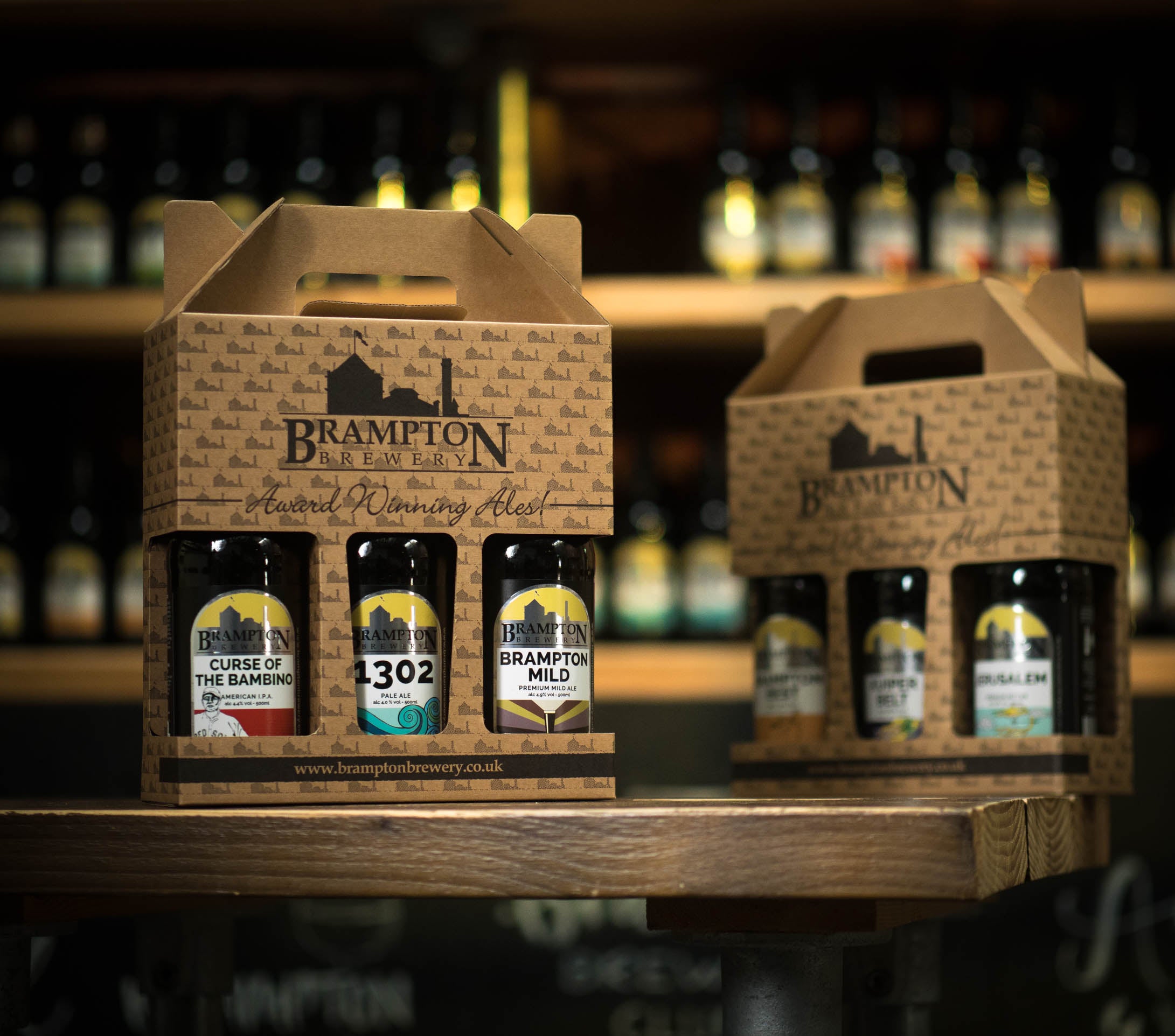 Two cardboard beer crates with bottles of Brampton beer on a wooden surface.
