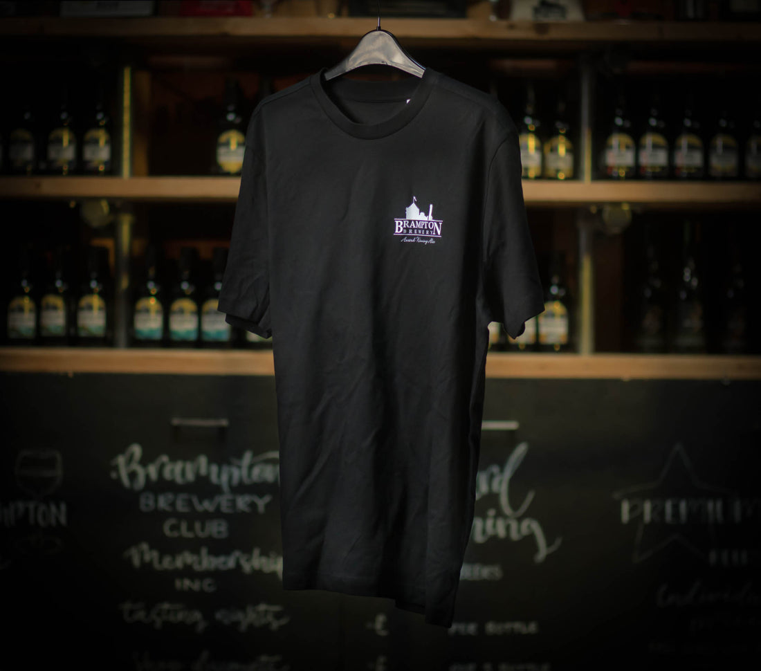 Black Brampton Brewery T‑shirt hanging in a rustic brewery setting, featuring the brewery’s logo and “Award Winning Ales” text.