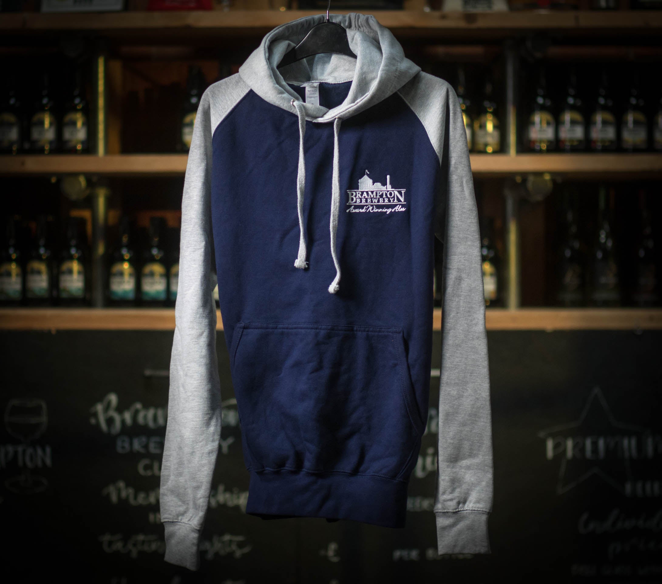 Navy and gray hoodie with a logo on a hanger against a bar background